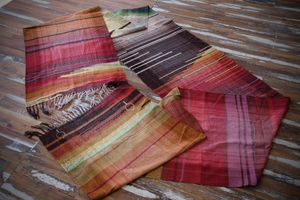 Handwoven diamond pattern fabric in rich shades of fall and earth laying on a wooden floor