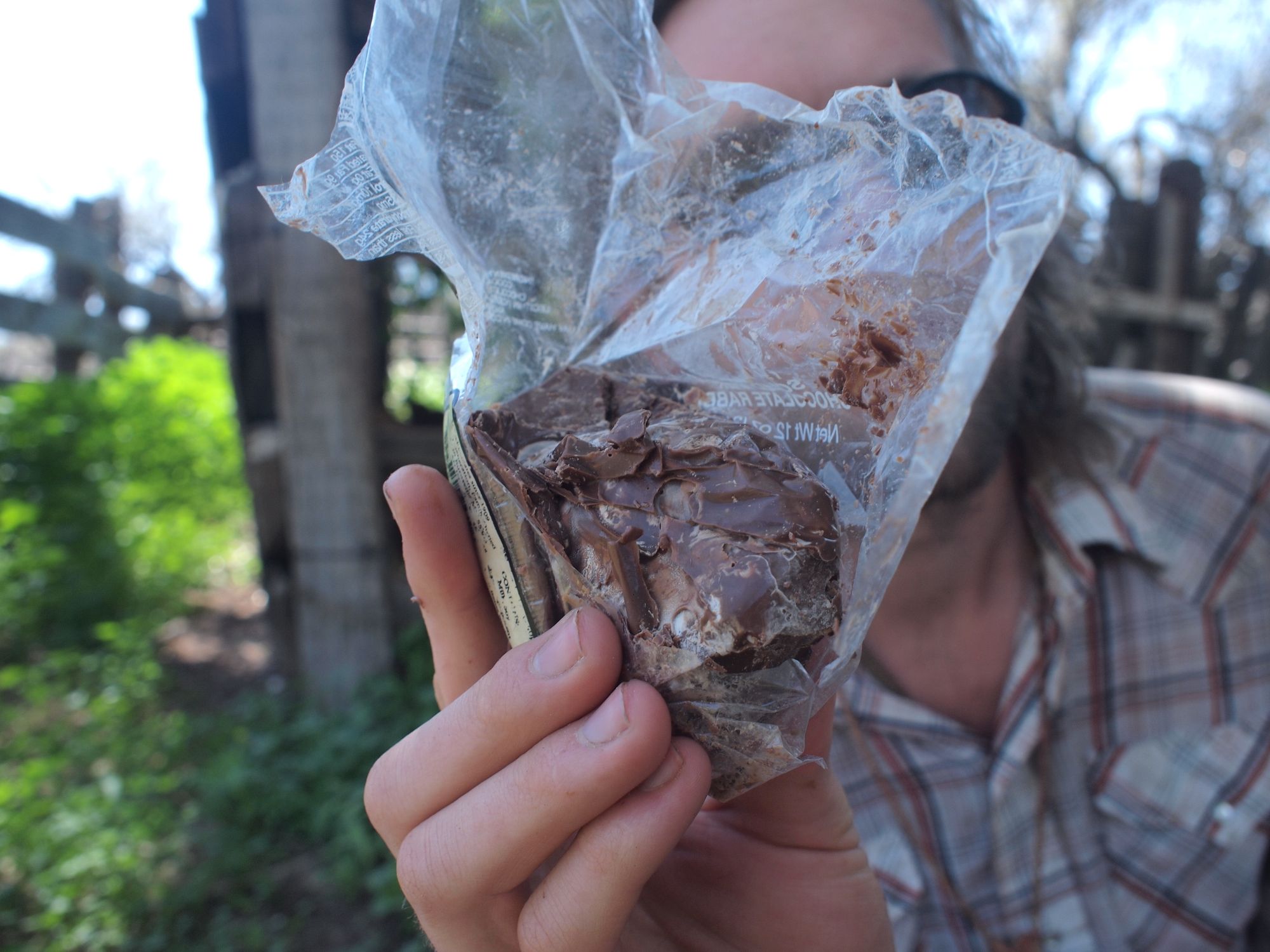 A man holds a melted lump of chocolate in front of his face