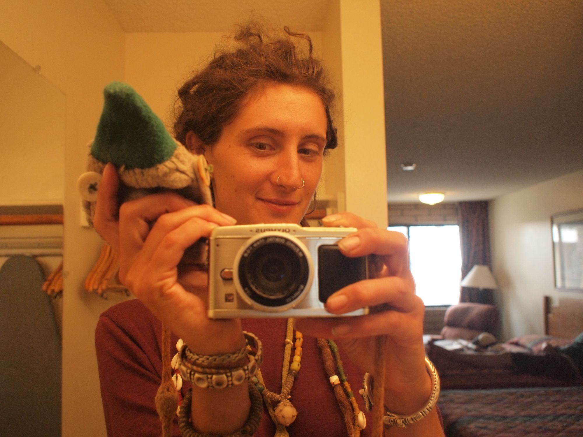 A woman wearing many necklaces and bracelets photographing herself in the mirror of a hotel bathroom