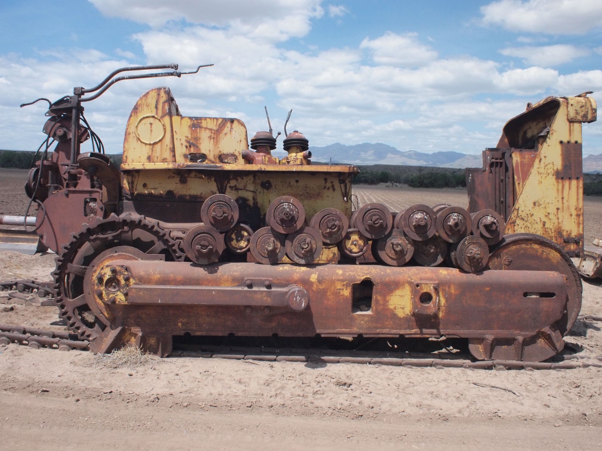 a yellow and rusty large machine in a cotton field 