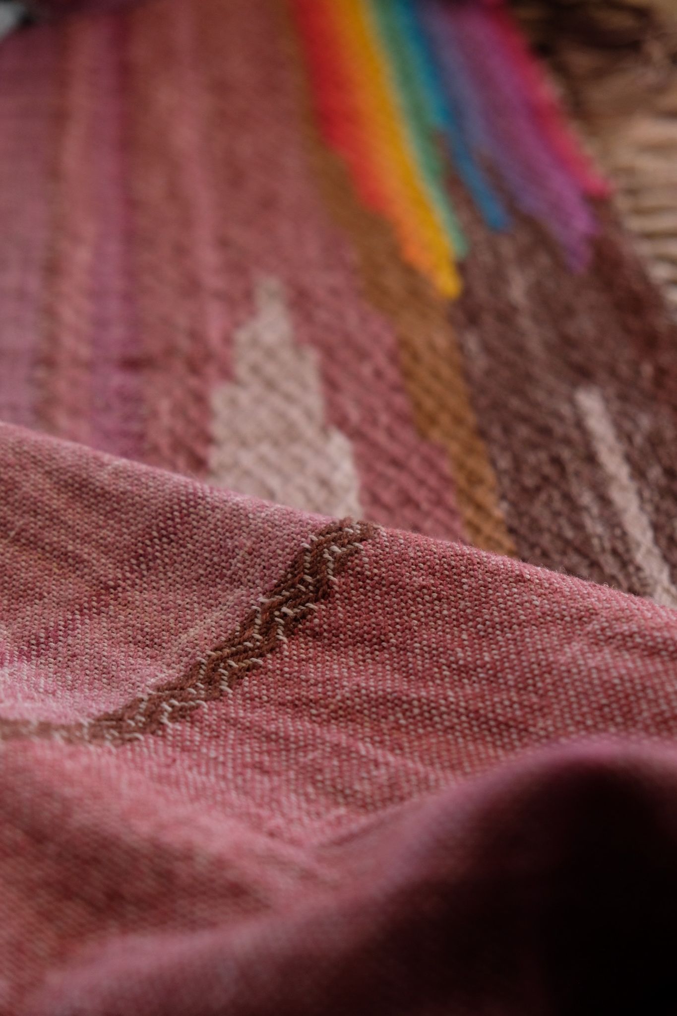 Brightly colored fabric in pink, yellow, orange, blue, cream, green and purple is laid out on a wooden floor