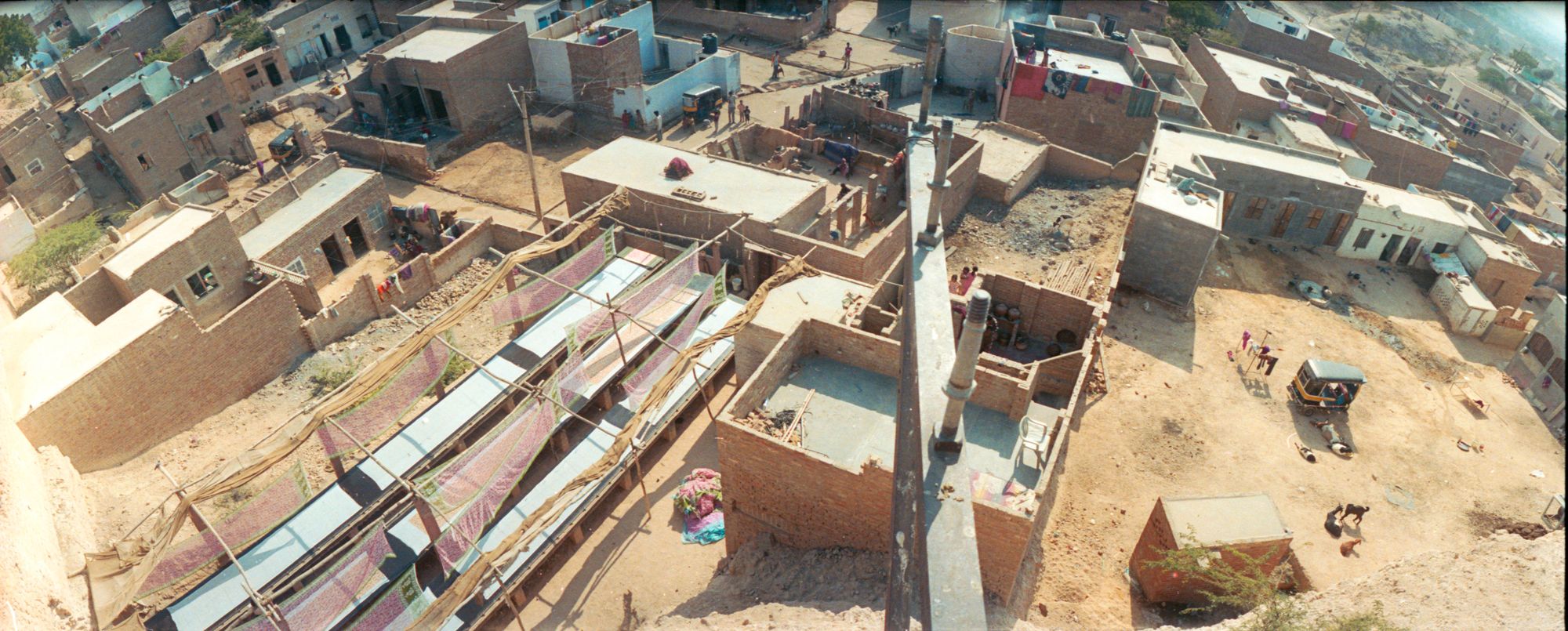 panoramic photo looking down onto a town in India, overlooking the tops of beige and grey buildings 