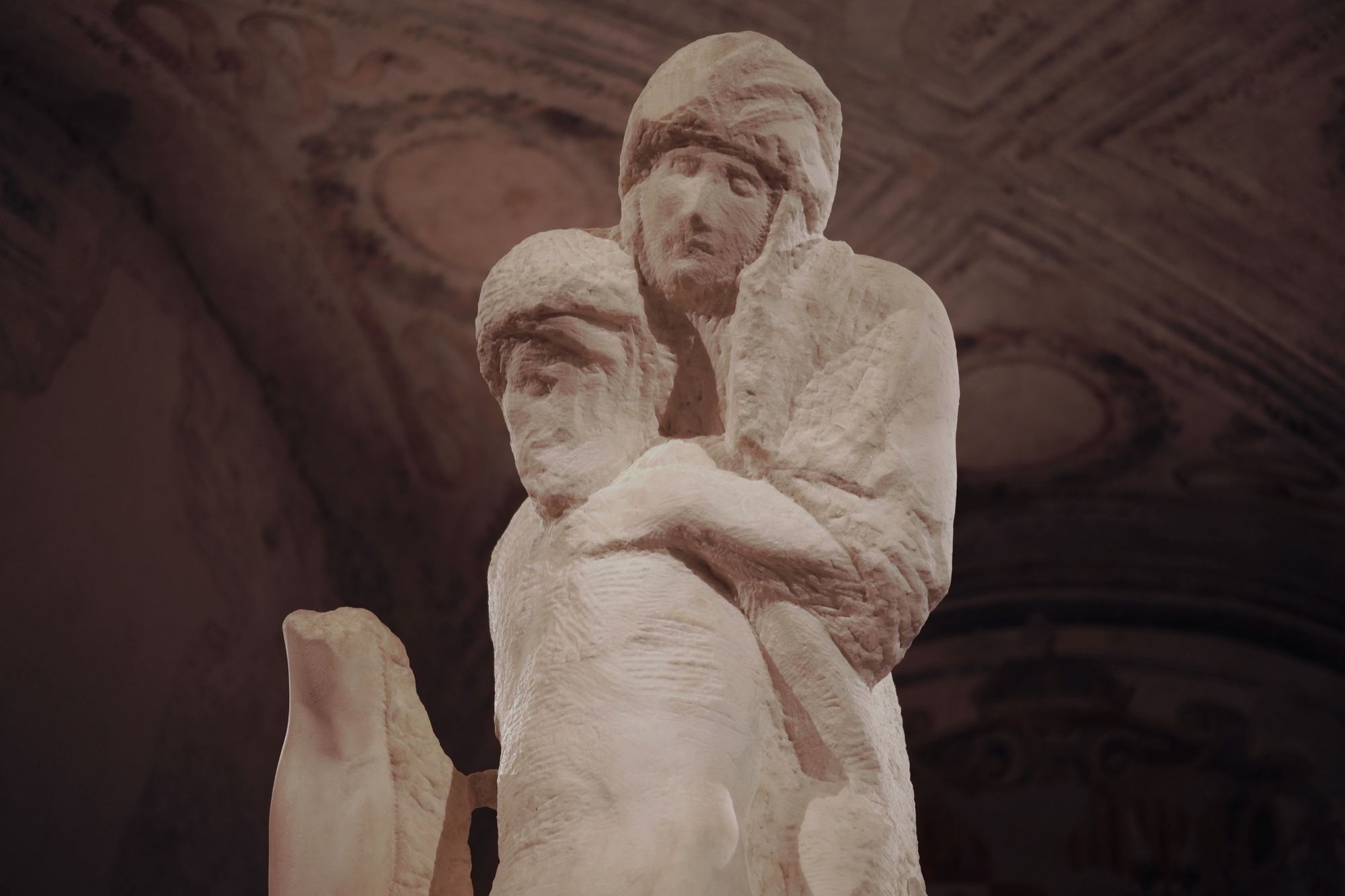 A stone sculpture of a mother standing above holding the limp form of her dead child. 