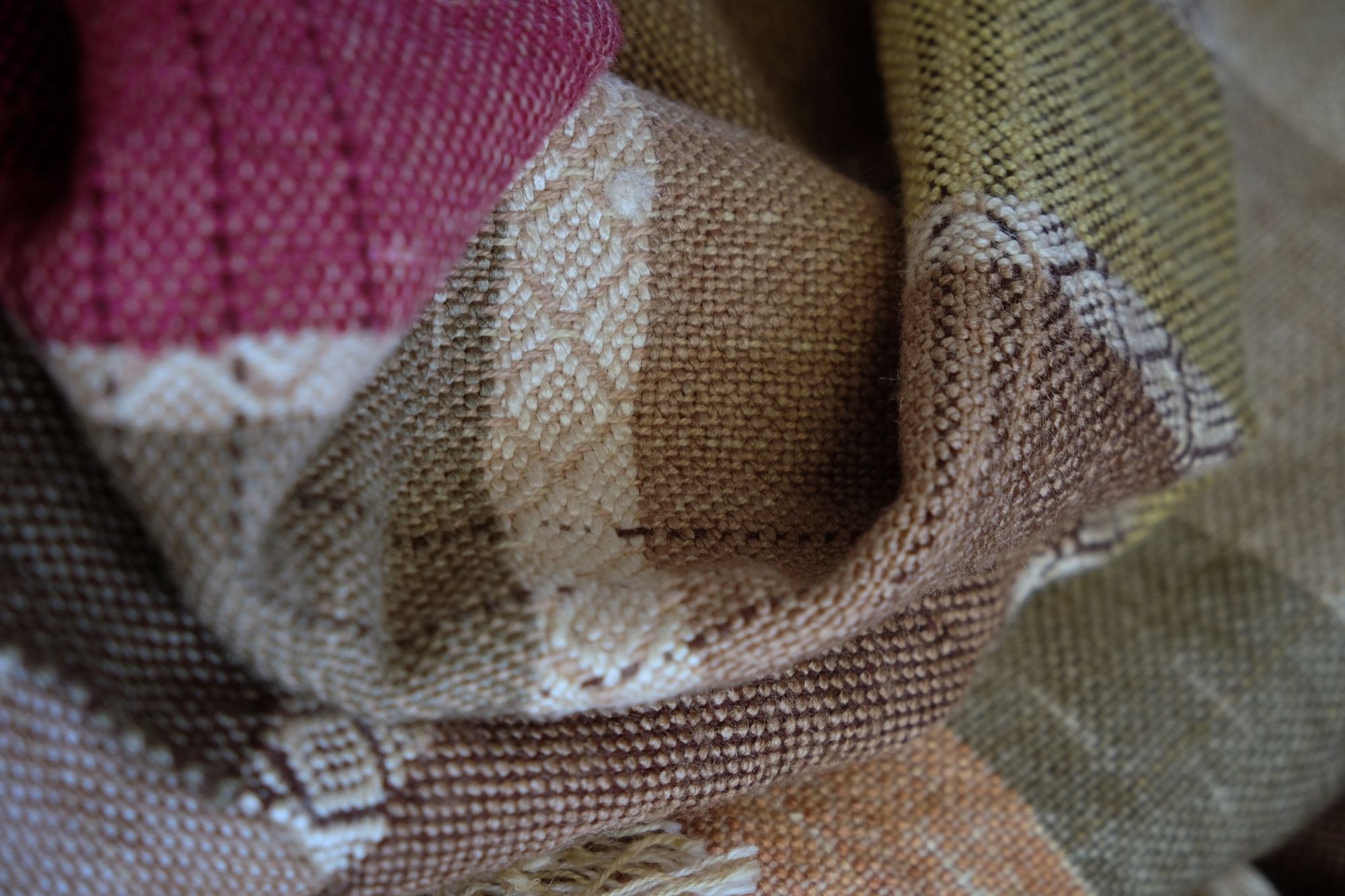 A detail of handwoven silk fabric in soft rainbow striped shades, naturally dyed