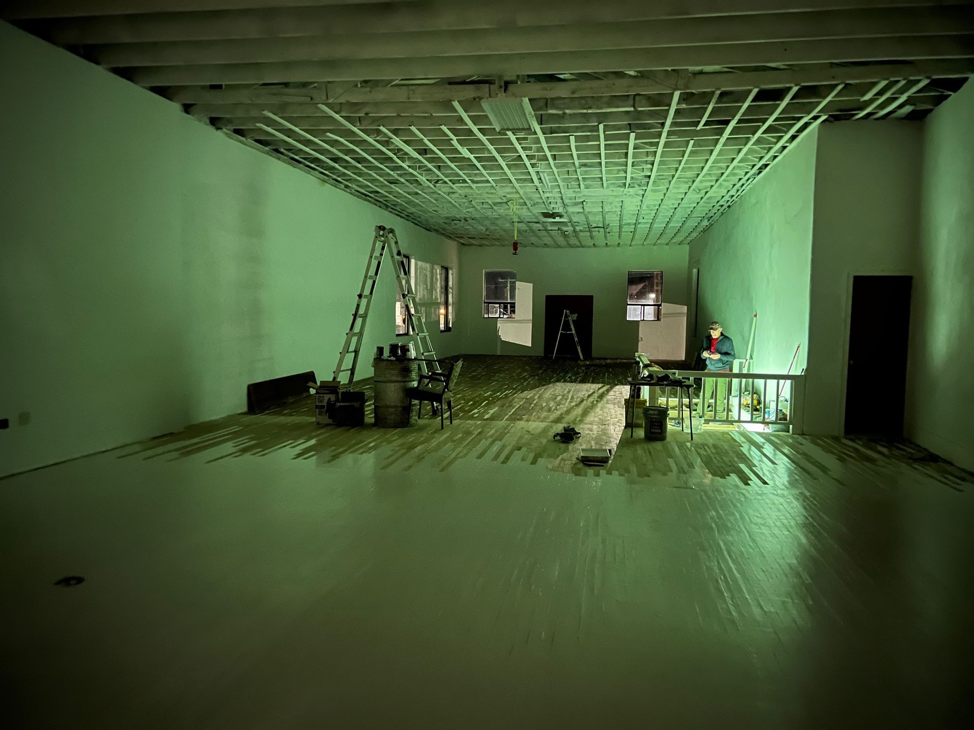 A room is filled with an eerie green glow from the basement below. 