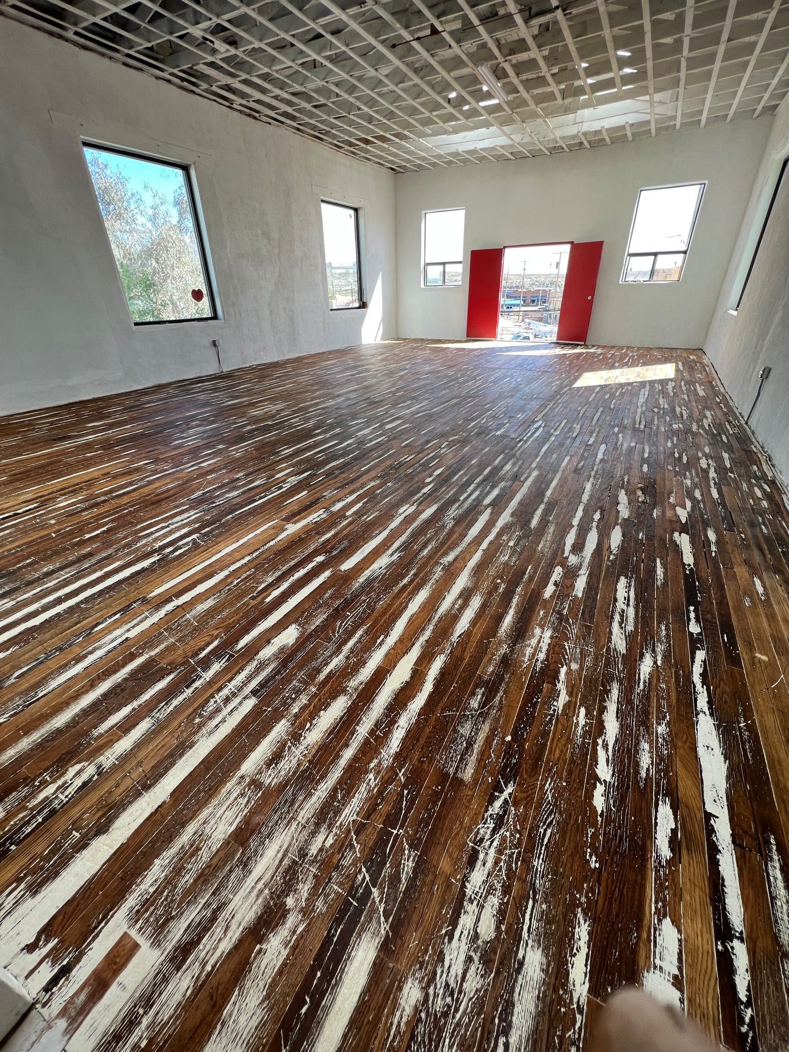 A large room with a freshly sanded wood floor that was then oiled.