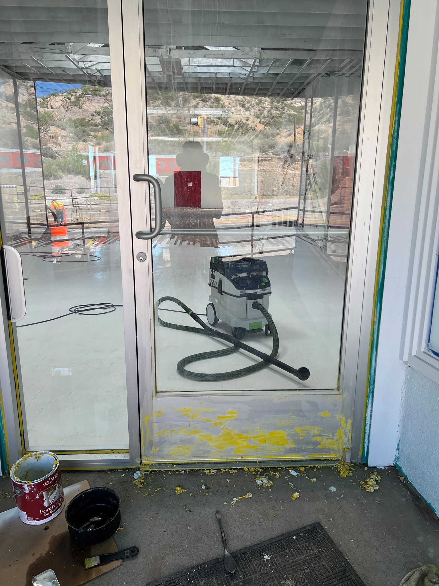 An aluminum door mostly stripped of yellow paint.