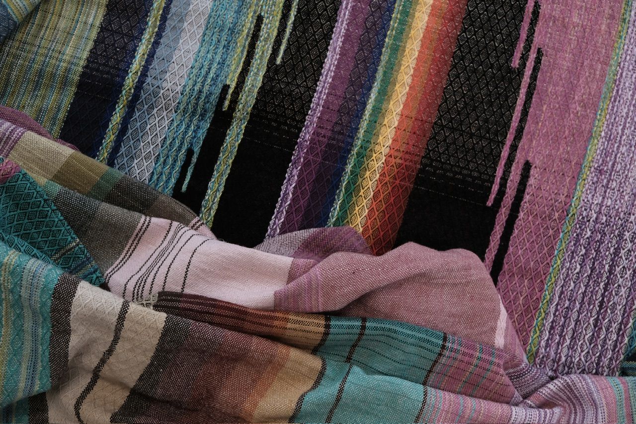 Rainbow and black handwoven fabric laying on a wood floor