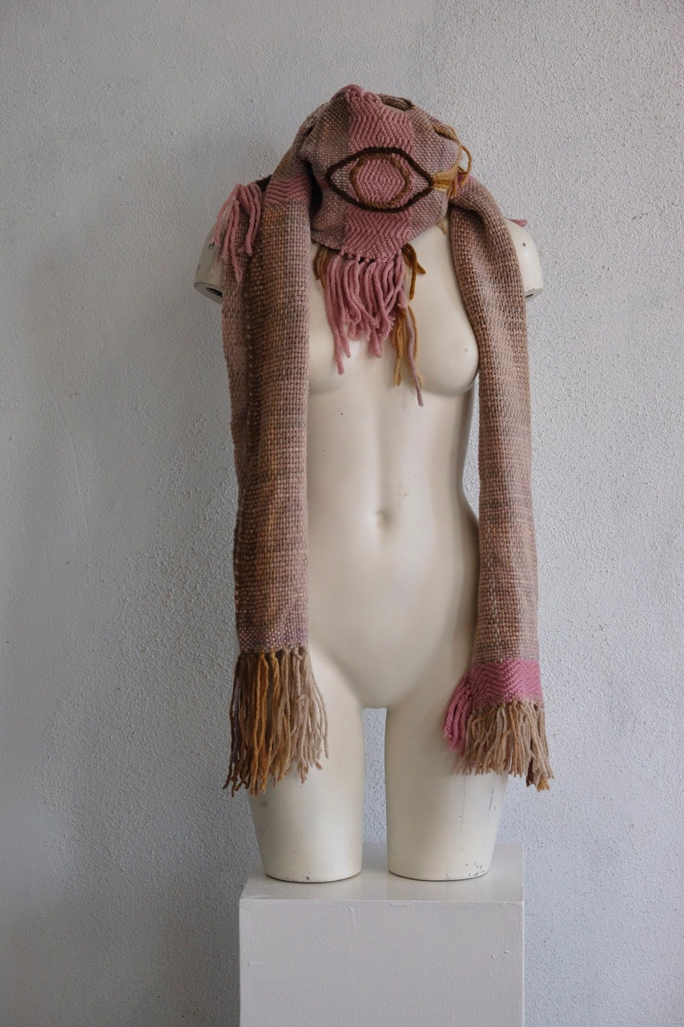 A softly colored chunky-sculptural scarf with thick braided and twisted rope-like details is displayed on a white painted mannequin