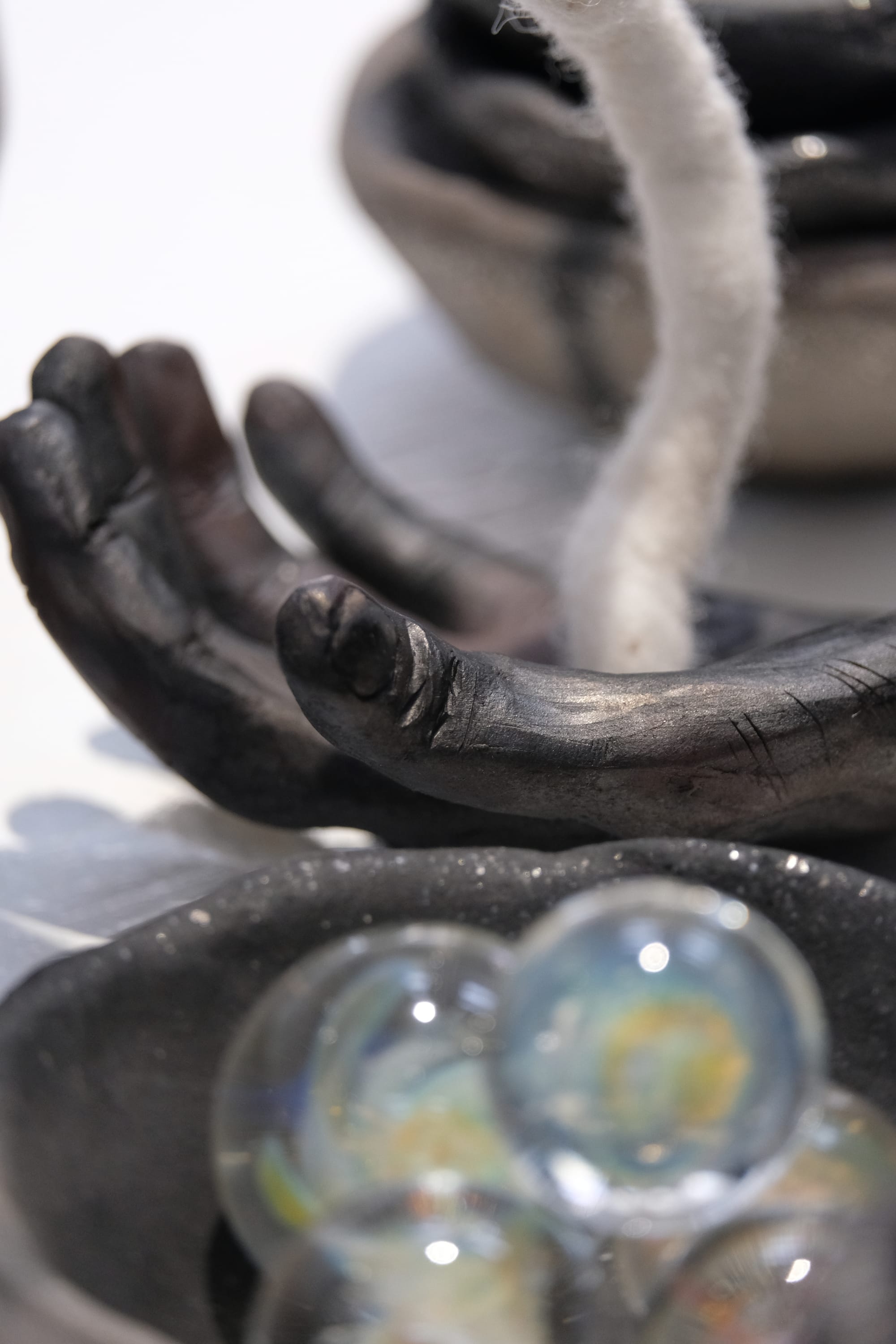 a close up image of a ceramic and glass art installation, the clay is shiny with mica and black from the firing. 