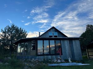 A house with corrugated metal front with many windows, a blue silver sunset reflecting in them, and seen above. 