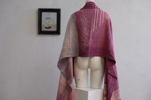 Handwoven fabric lays on a white mannequin The fabric is naturally dyed with cochineal in all shades of pink and fuchsia